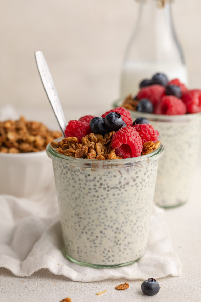 chia seed protein pudding in a glass jar with fresh blueberries and homemade granola on top.