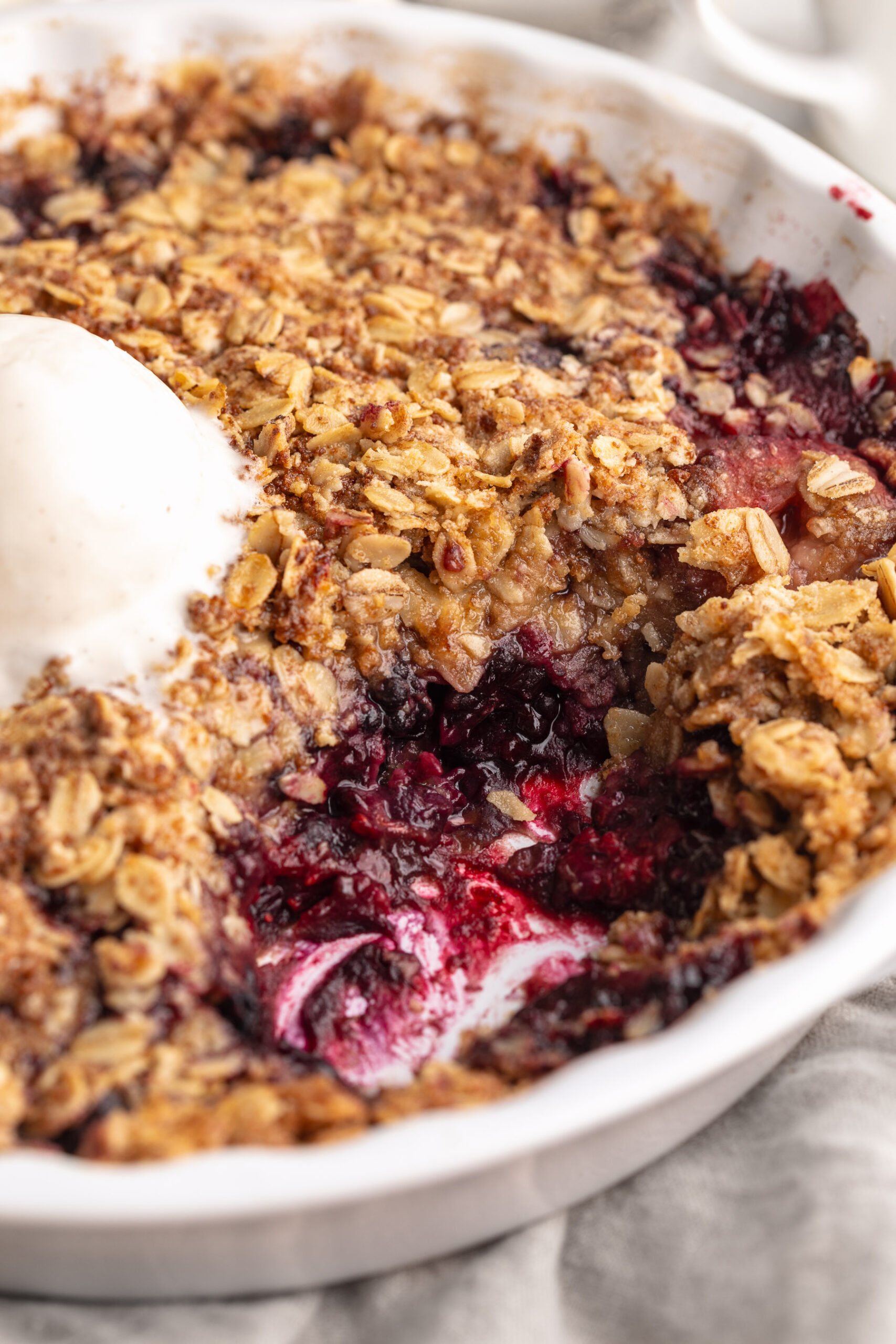 close up image of triple berry crisp with frozen berries in a baking dish.