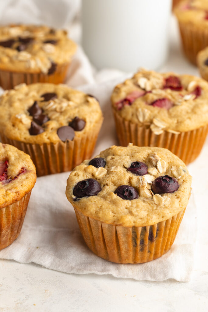 healthy oat breakfast muffins on a white towel with blueberries.