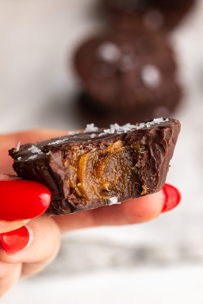 hand holding a healthy date caramel cup with a bite taken out.