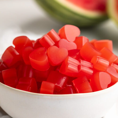 small bowl of 3 ingredient healthy watermelon gummies with fresh watermelon on the side.