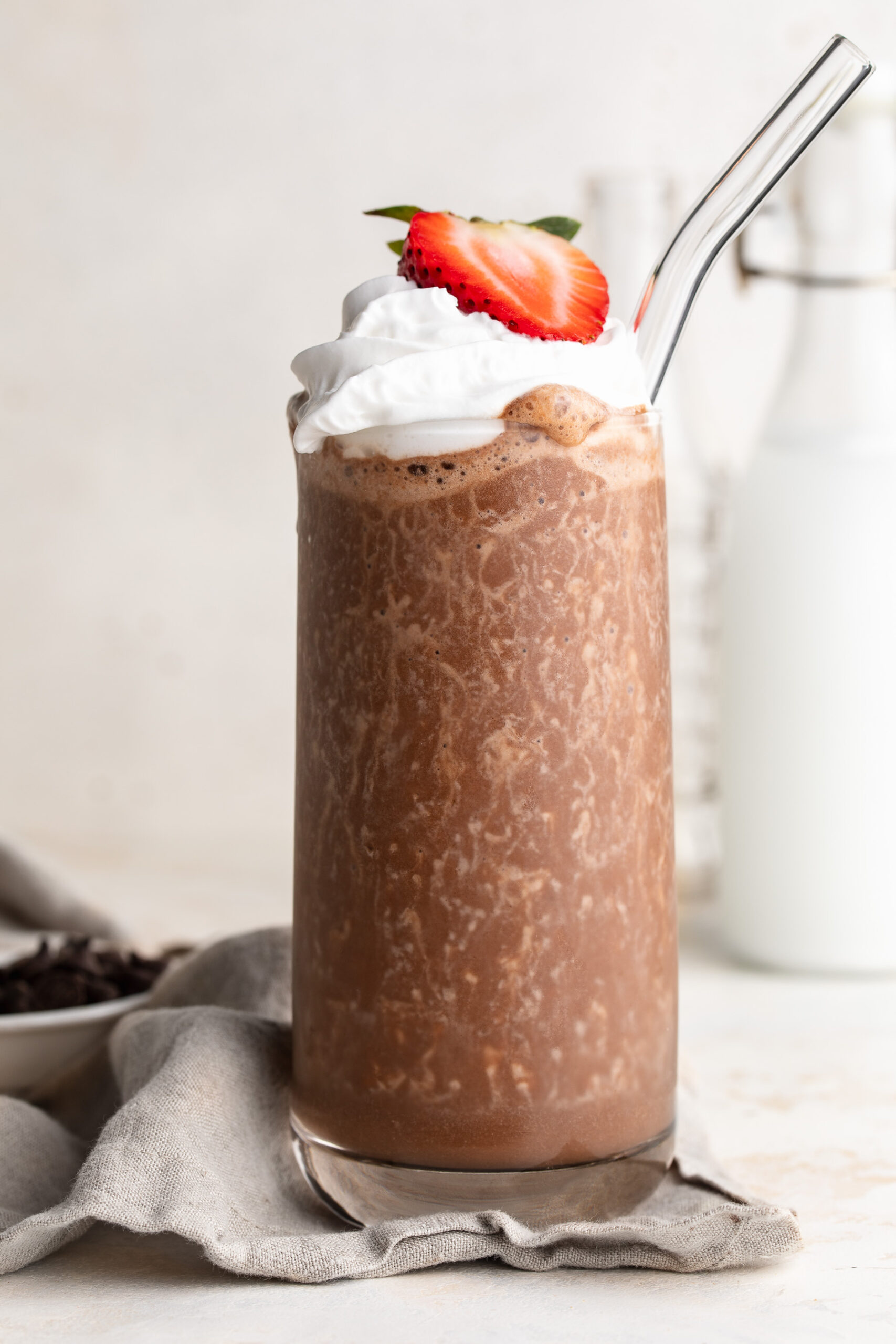 healthy milkshake in a glass with whipped cream and a strawberry on top.
