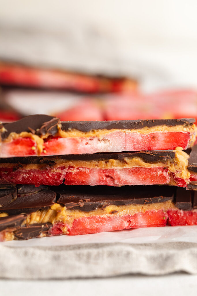 three pieces of healthy strawberry peanut butter chocolate bark on top of each other.