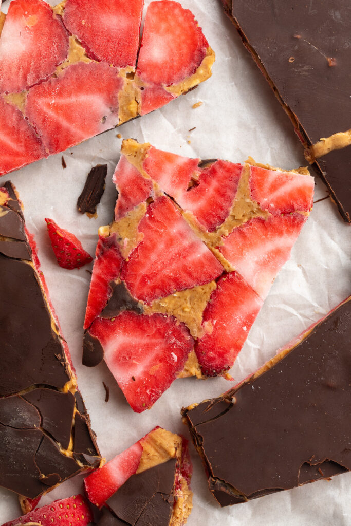 overhead image of pieces of healthy strawberry peanut butter chocolate bark on parchment paper.