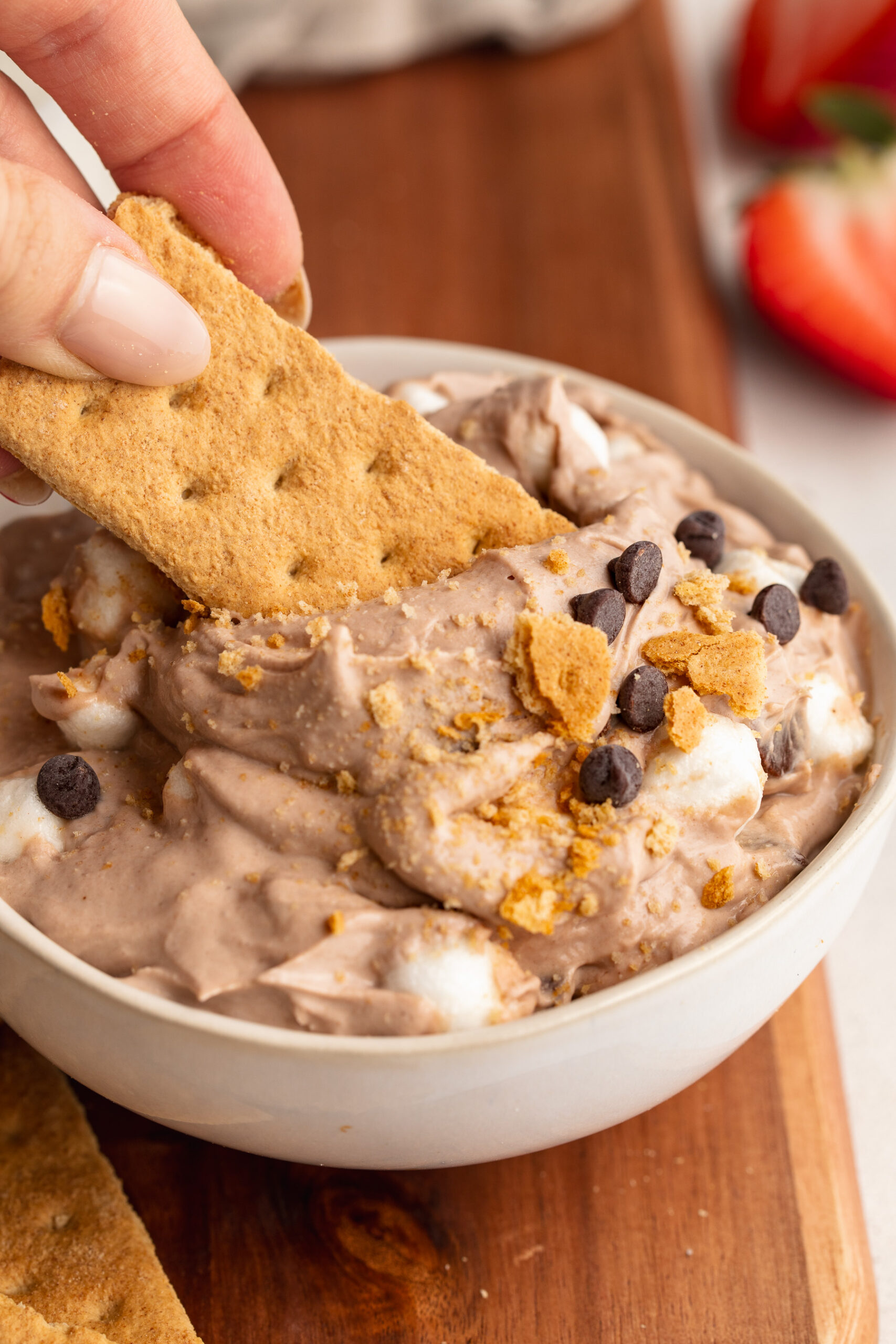 graham cracker being dipped into high protein s'mores dip.