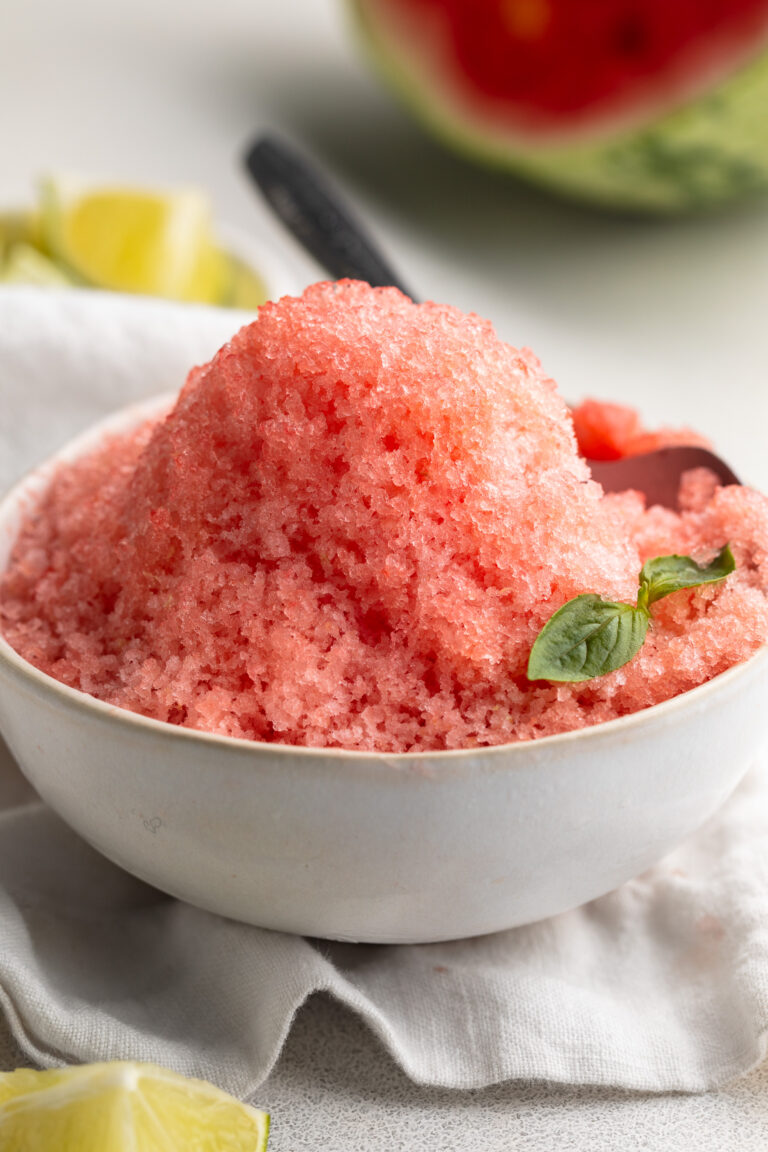 watermelon shaved ice in a small bowl with a sprig of fresh mint.