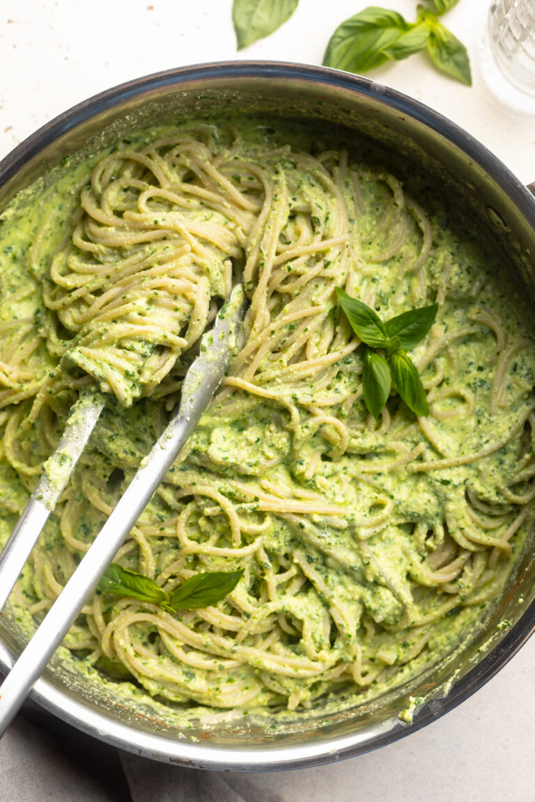 overhead image of protein pesto pasta in a skillet with fresh basil on top.