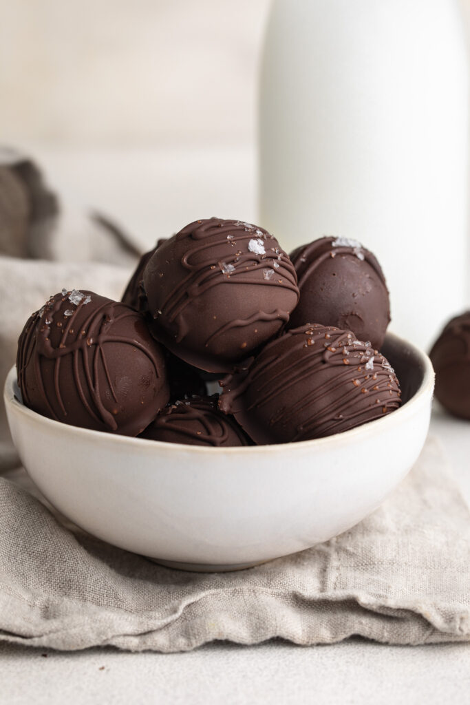 healthy no-bake brownie balls in a small bowl with flaky salt on top.