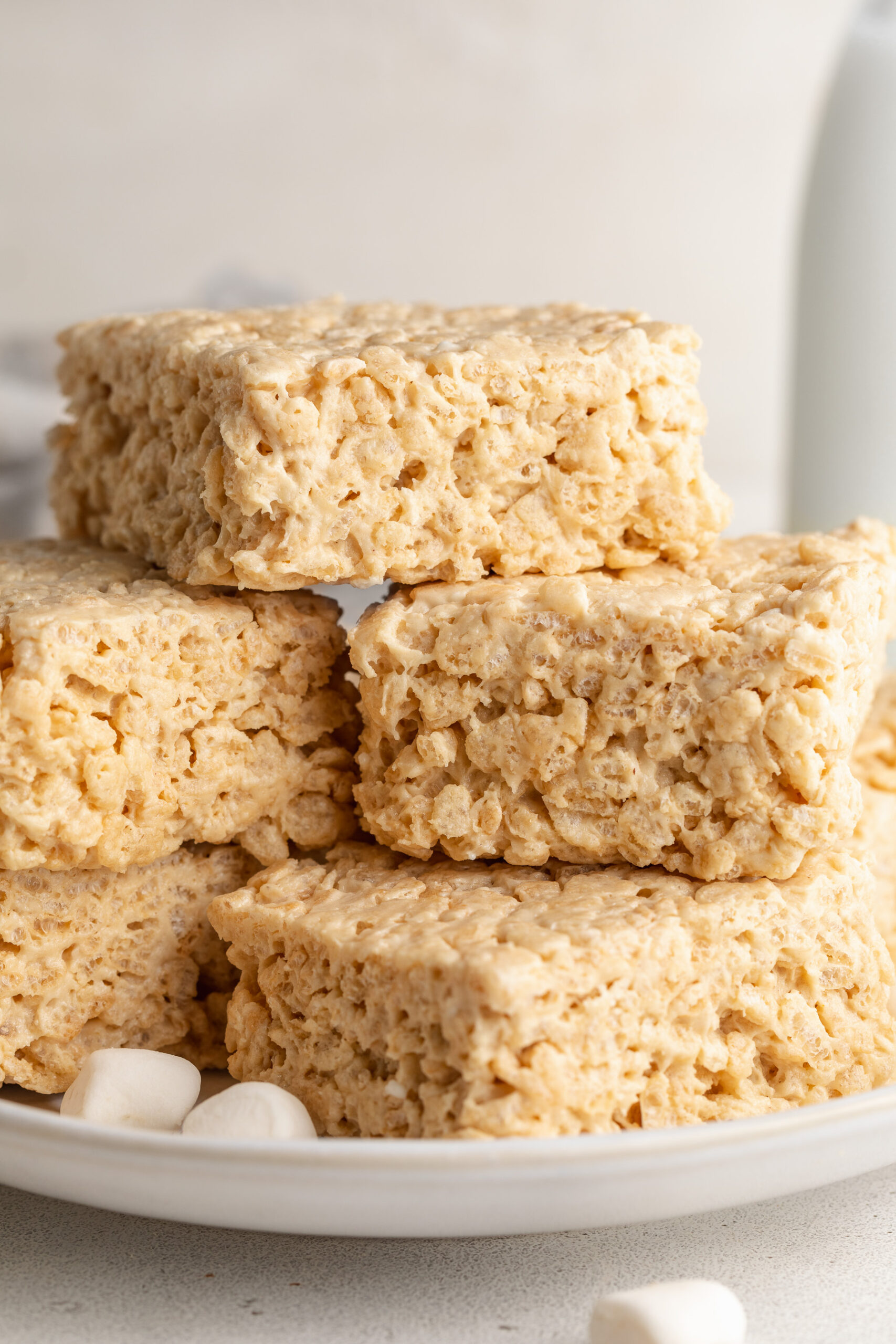 protein rice crispy treats stacked on a plate with mini marshmallows.