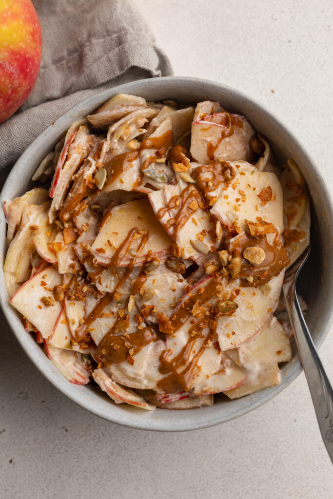 overhead image of healthy apple pie salad in a bowl with an apple on the side.