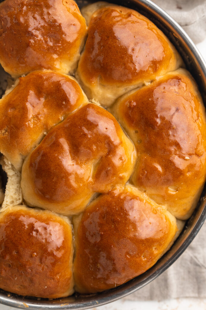 overhead image of gluten-free dinner rolls in a baking dish with dairy-free butter brushed on top.