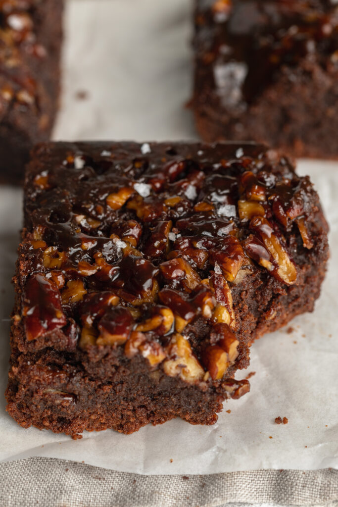 close up image of a sticky pecan pie brownie with a bite taken out.