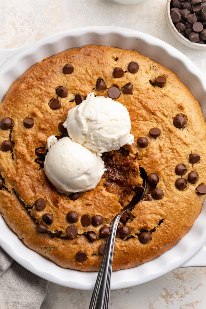 overhead image of healthy cookie pie in a pie dish with ice cream on top.