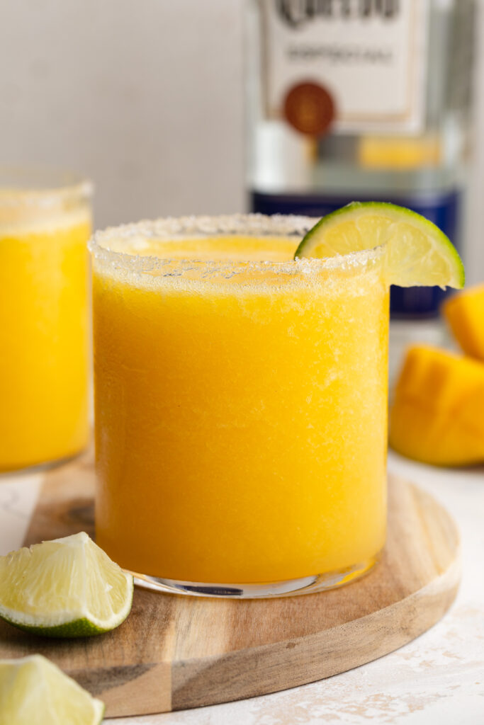 mango margaritas in a glass with a line on the rim.