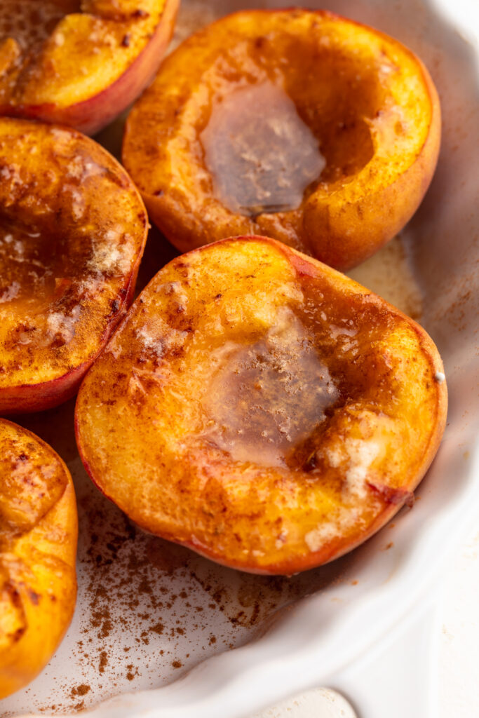 close up image of baked peaches in a baking dish.